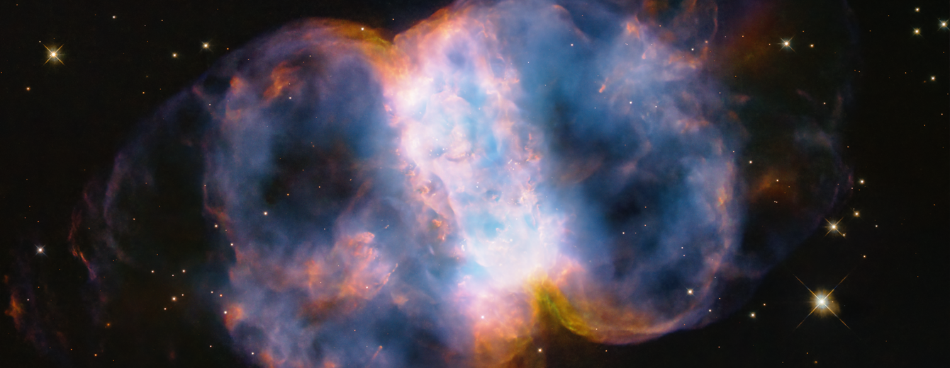 Taking up most of the image, is a multi-colored nebula appearing as two translucent orbs attached by a white band.