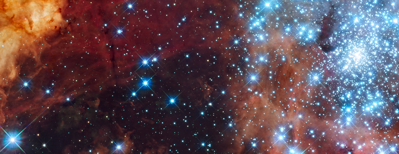 Thick, fluffy orange and brown material stretch across the top and drape down the sides of the image. Toward the right is a bright star cluster. Near the center of the cluster, the stars are so close together that they appear as an amorphous blob of blue-white light. Moving away from the center, the stars are spread apart. Toward the lower left side, the density of stars is the lightest and the dark background of space can be seen.