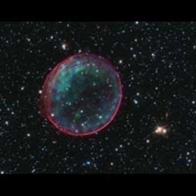Supernova remnant resembling a bubble. Its exterior is tinged with red, while its interior has blue-green blotches.