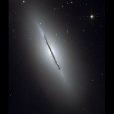 An edge-on spiral galaxy with a thin, clumpy line of dust stretches from upper left to lower right.