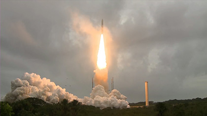 Photo of Ariane 5 rocket carrying Webb telescope launching into a cloudy sky.