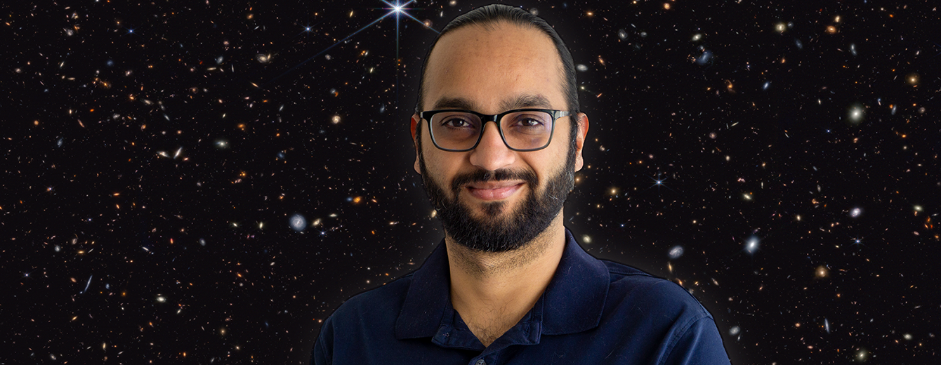 Headshot of a gentleman with black hair, mustache, beard, and glasses against a dark sky field featuring a multicolored sea of galaxies.
